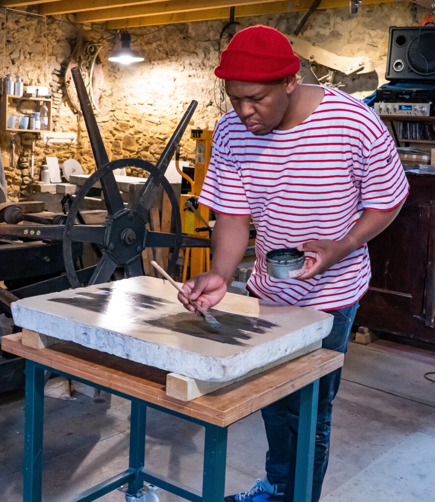 Mongezi Ncapahyi drawing on the lithographic stone at Atelier le Grand Village