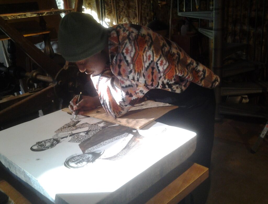Bambo Sibiya drawing on the stone at Atelier le Grand Village