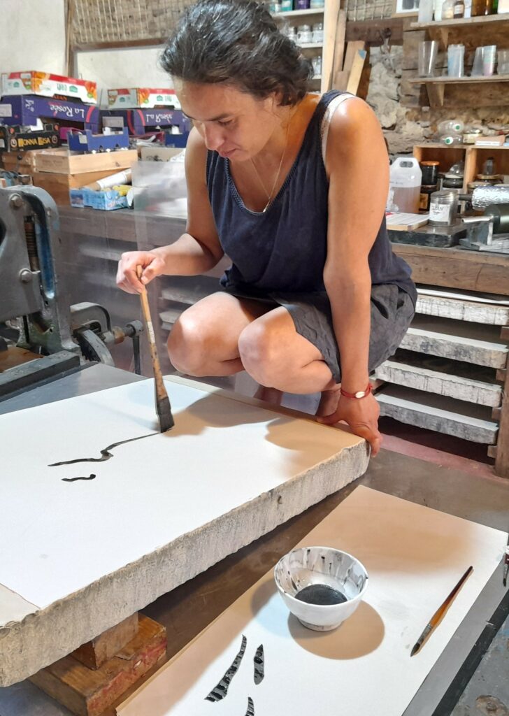 Dalila Dalléas Bouzar drawing on the lithographic stone at Atelier le Grand Village
